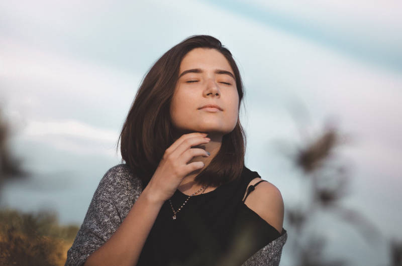 Jeune femme épanouie, yeux fermée et heureuse